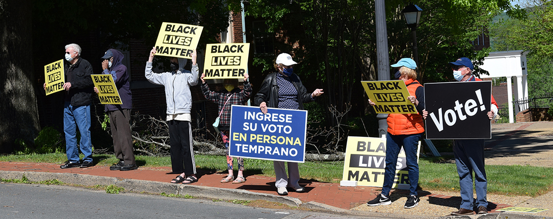BLM activists holding signs along a residential street including Black Lives Matter and voting signs